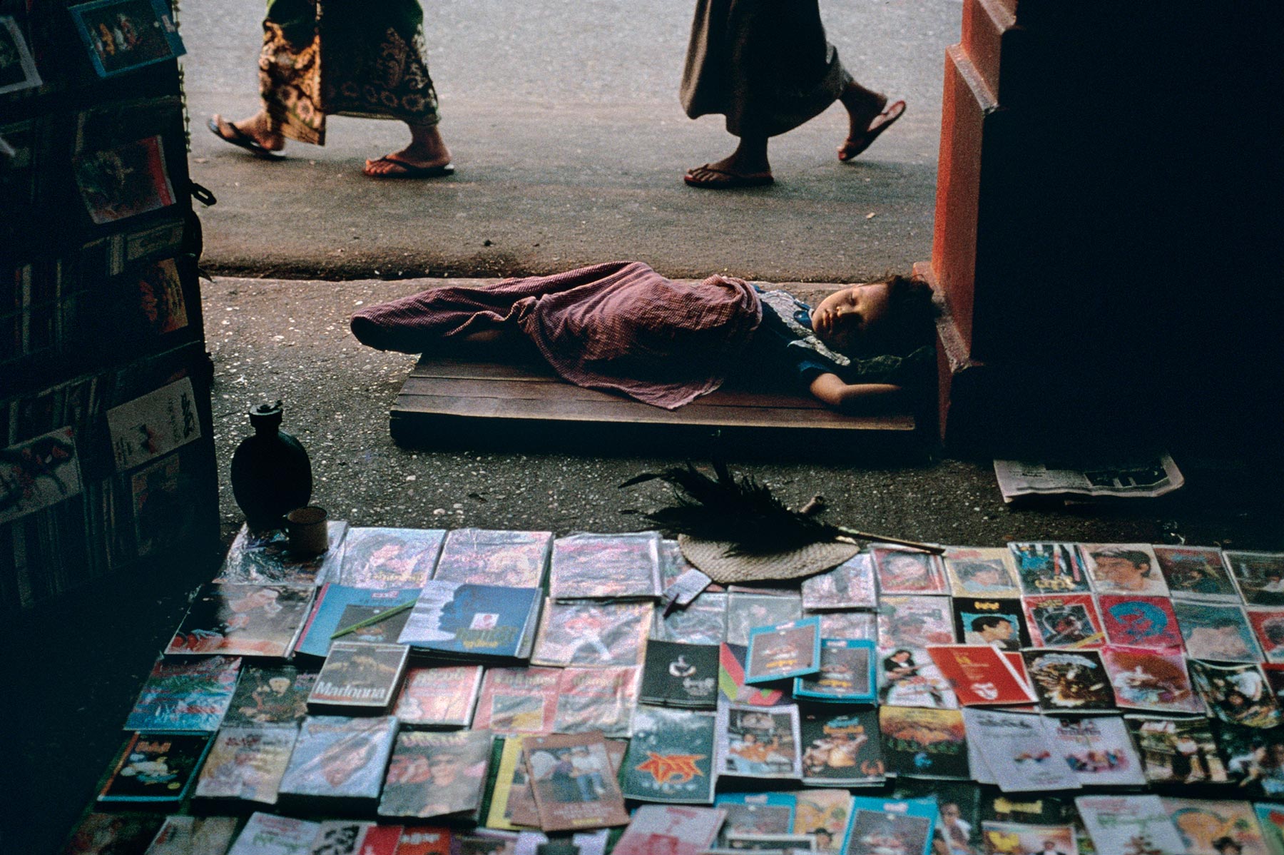  小摊边熟睡的孩子，仰光，缅甸。<br/>摄影师Steve McCurry。 