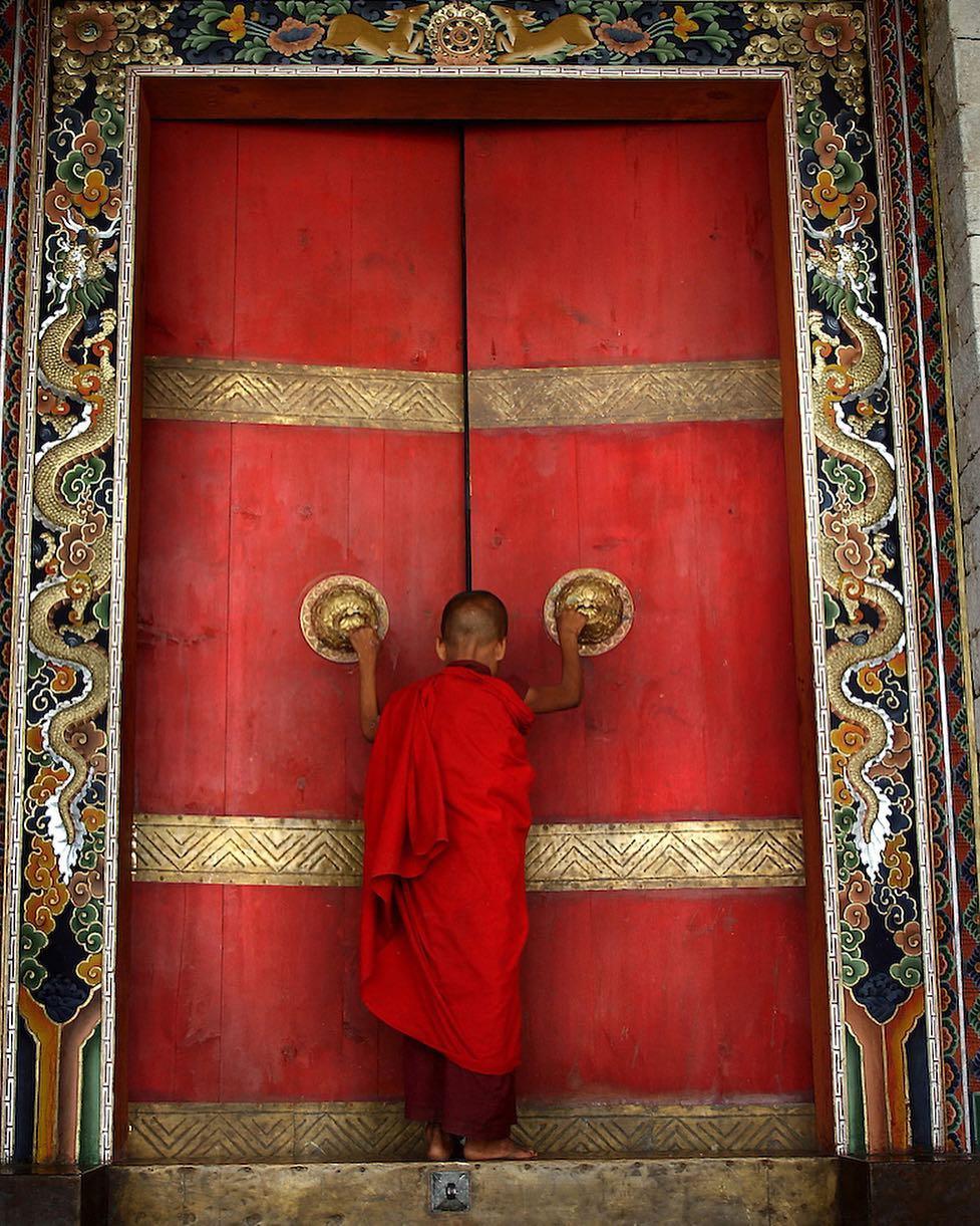  推开寺庙大门的和尚，Ami Vitale摄于不丹同萨。 