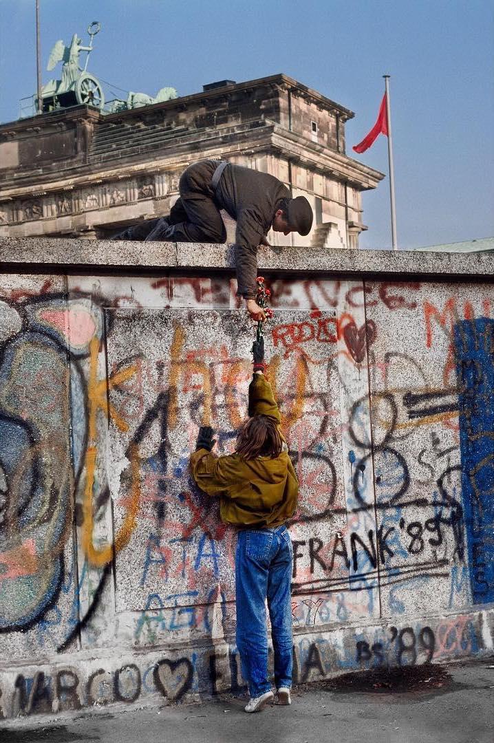  递花给东德士兵的女人，Steve McCurry摄于1989年德国柏林。 