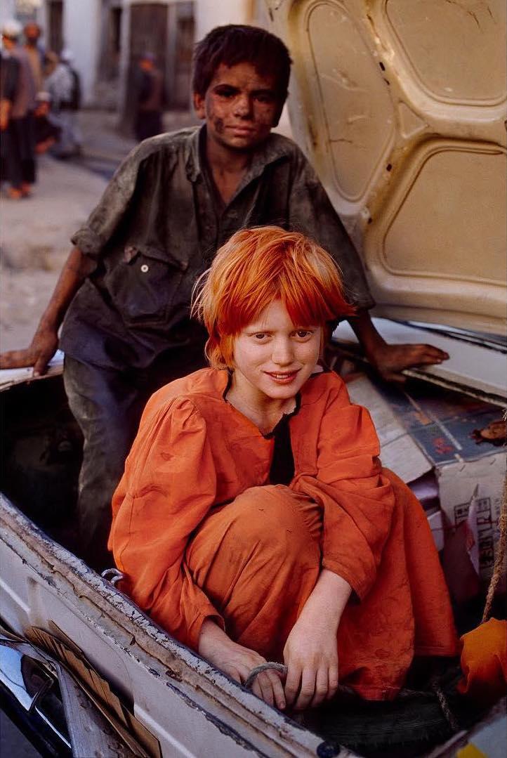  从集市中坐在车厢里回家的女孩和她的哥哥，Steve McCurry摄于2002年阿富汗。 