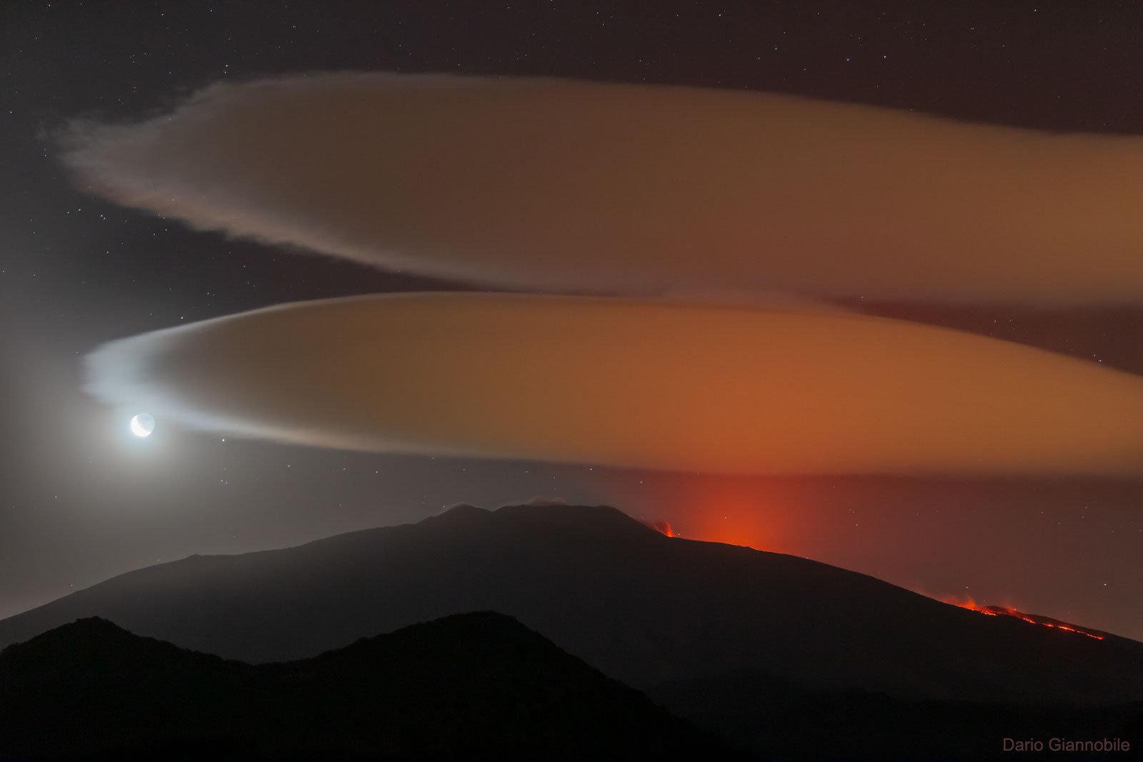  埃特納火山上空的莢狀雲 <br />影像提供與版權: Dario Giannobile <br />說明: 這座火山的上空發生了什麼事？ 雖然埃特納火山正在爆發，但它上空的雲和此次的爆發無關。 它們是潮濕空氣受迫沿著山峰或火山抬升，所形成的莢狀雲。 這幅超現實的景觀，是在上個月當這位天文攝影者，前往義大利．西西里島的聯合國教科文組織 世界文化遺址埃特納火山，拍攝月亮和畢宿五近合時補捉到的。<br /> 