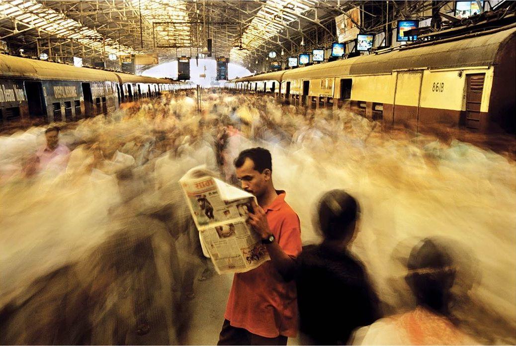  车站人流中看报的人，来自摄影师Raghu Rai。 