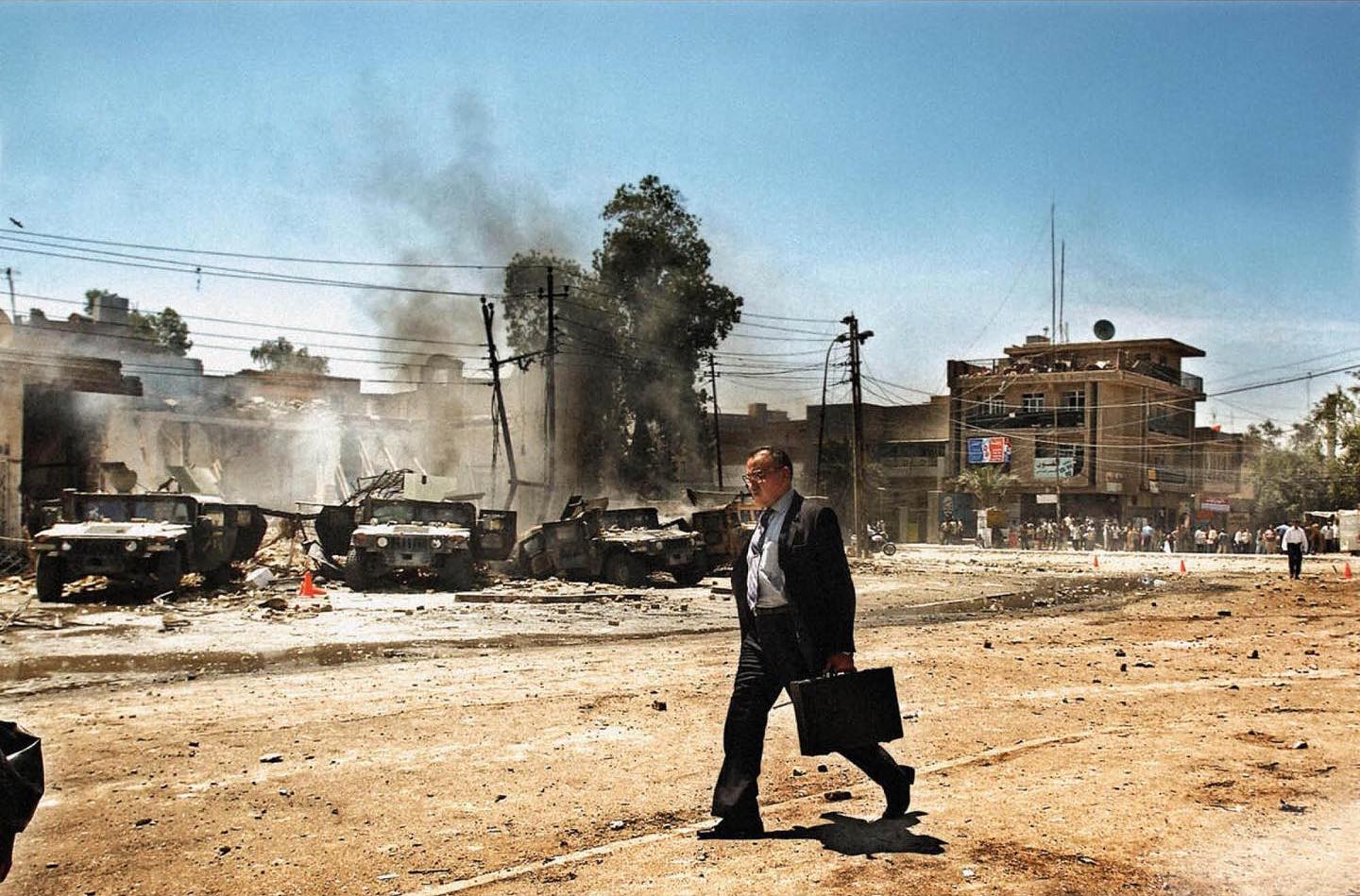  从被炸毁的悍马车前路过的男子，Moises Saman摄于2004年伊拉克巴格达。 